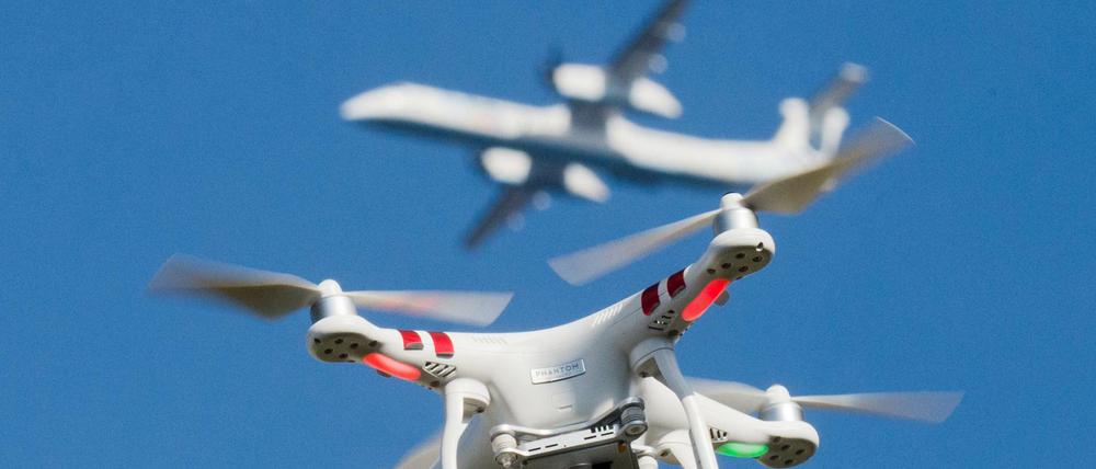 Eine private Drohne fliegt in Nordrhein-Westfalen, im Hintergrund ist ein Flugzeug beim Anflug auf den Flughafen Düsseldorf zu sehen. 