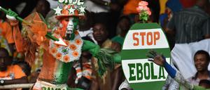 Ein Anhänger der Nationalelf der Elfenbeinküste hält ein Schild, um für einen stärkeren Kampf gegen die Ebola zu demonstrieren.