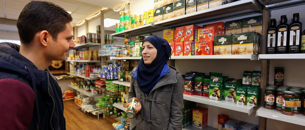 Zainab Shami, Inhaberin des Die syrischen Asylbewerber Rami Al Issa (l) und Iman Alramadan kaufen im Lebensmittelgeschäft "Damaskus" in Sigmaringen (Baden-Württemberg) ein.
