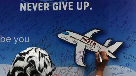 Eine Frau schreibt während einer Gedenkveranstaltung zum Flug MH370 eine Nachricht auf ein Banner. (Archivbild)