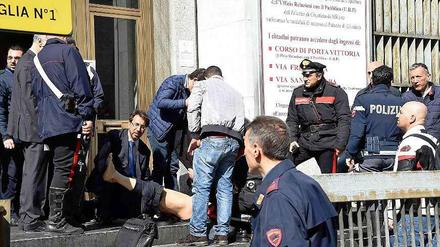 Rettungskräfte und Polizisten helfen einem Verwundeten auf dem Gerichtsgebäude in Mailand. 