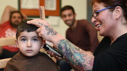 Friseurin Susanne Toraman schneidet am 28.09.2015 in Bremen dem zweijährigen Masoum aus Syrien die Haare. Einmal die Woche schneidet Toraman Flüchtlingen in einem Übergangswohnheim kostenlos die Haare.