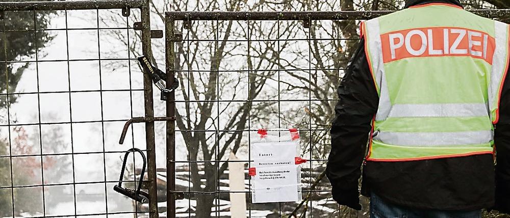 Ein Polizist vor einem abgesperrten, privaten Grundstück in der Nähe von Arnstein (Landkreis Main-Spessart) bei Würzburg. Nach dem Fund von sechs Toten in einer Gartenlaube in Unterfranken ist die Todesursache nun geklärt.