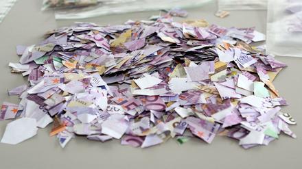 Zerrissene und zerschnittene Geldscheine auf einem Tisch der Polizei in Darmstadt. An insgesamt 23 Stellen in der Stadt wurden Teile von Geldscheinen gefunden. 