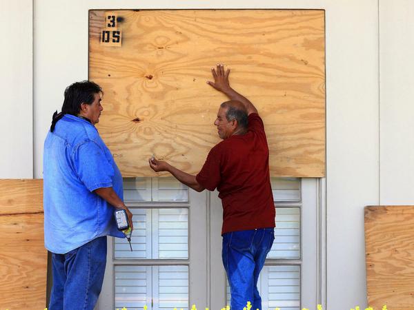 Zwei Männer sichern in Texas mit Holzplatten die Fenster ihres Hauses