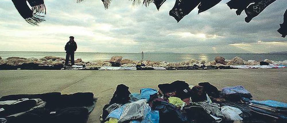 Am Minimum. Ein chinesischer Einwanderer verkauft an einem Strand vor Athen Kleider. 