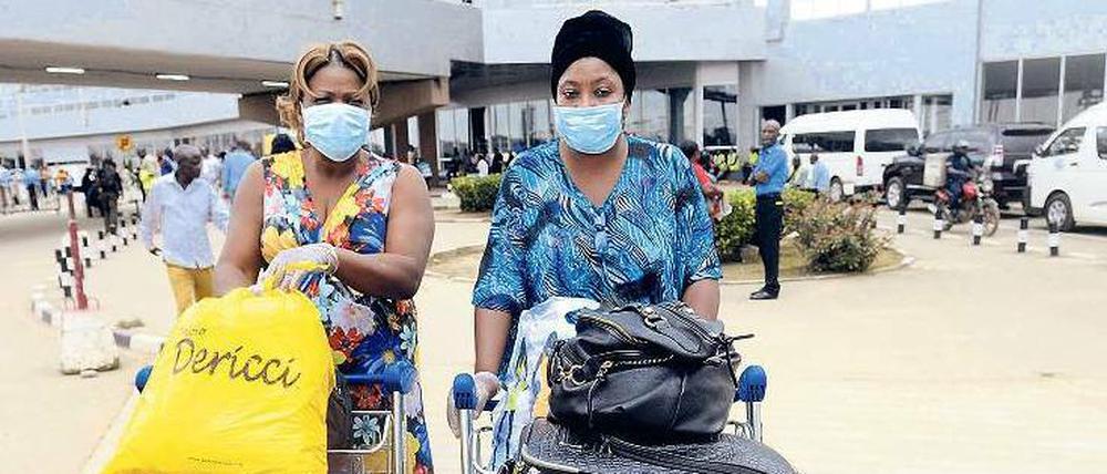 Leben mit Ebola. Zwei Frauen bereiten sich auf dem Flughafen in der nigerianischen Millionen-Stadt Lagos auf ihren Abflug vor. Auch das Sicherheitspersonal tritt derzeit mit Mundschutz und Einmal-Handschuhen seinen Dienst an. 