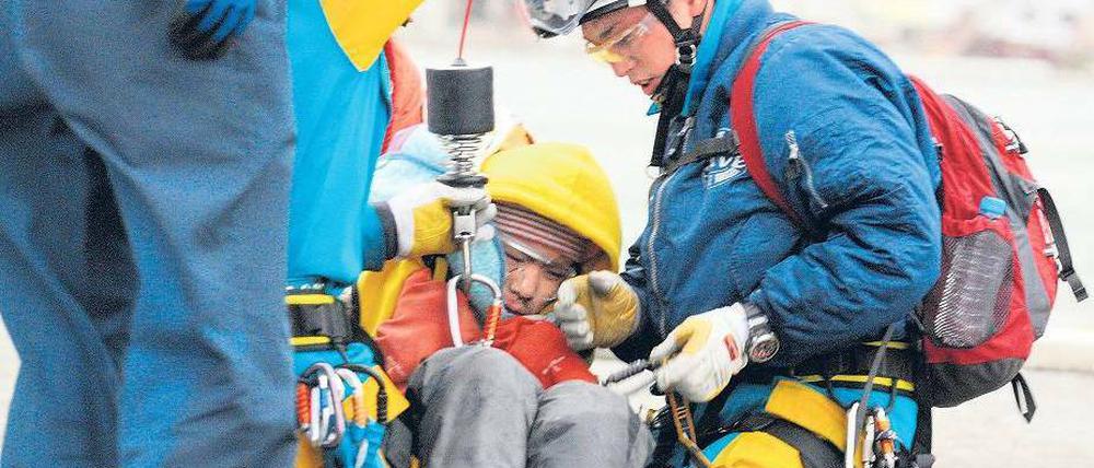 In Sicherheit. Helfer schlingen einen Gurt um den 16-jährigen Jin Abe, der anschließend mit einem Hubschrauber abtransportiert wird. Der Junge war gemeinsam mit seiner Großmutter von Einsatzkräften aus den Trümmern eines Hauses in Ishinomaki befreit worden. Foto: dpa/Asahi Shimbun