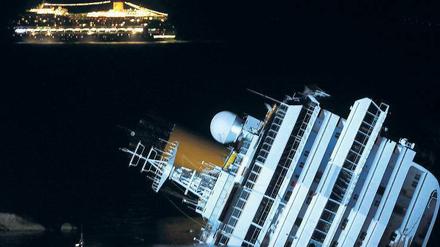 Unbeirrt. Während die Costa Concordia auf dem Felsen liegt, fährt ihr Schwesterschiff Costa Serena hell erleuchtet vorbei. Das Schiff fährt dieselbe Route wie die Costa Concordia und bietet das gleiche Programm. 