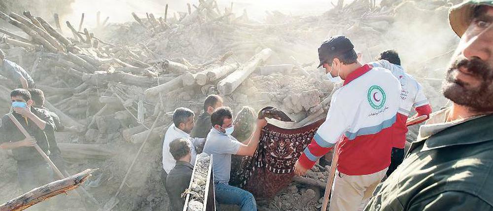 Graben mit bloßen Händen. Helfer in dem Ort Bajeh Baj bergen mit einem Teppich ein Bebenopfer. 