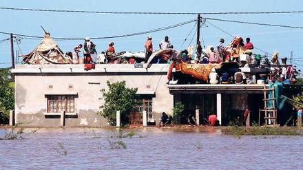 Menschen sind auf ein Hausdach geflüchtet, um den Fluten zu entkommen. 