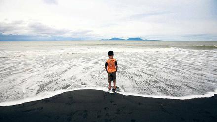 Todesstrand. Ein Kind steht am Wasser anlässlich der Trauerfeiern in Syiah Kuala in der indonesischen Provinz Aceh. Diese war vom verheerenden Tsunami vor zehn Jahren besonders betroffen.