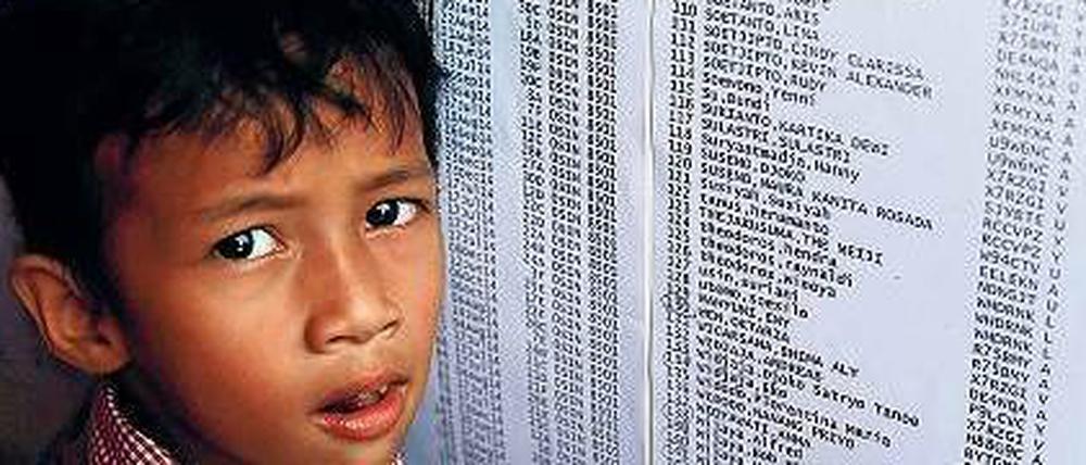 Ein Junge schaut auf die am Flughafen in Surabaya ausgehängte Passagierliste. 