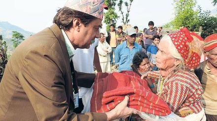 Für sie. Ein Helfer einer lokalen Partnerorganisation der Deutschen Welthungerhilfe (DWHH) übergibt einer alten Frau an einer Ausgabestelle nahe Kathmandu eine Decke. 
