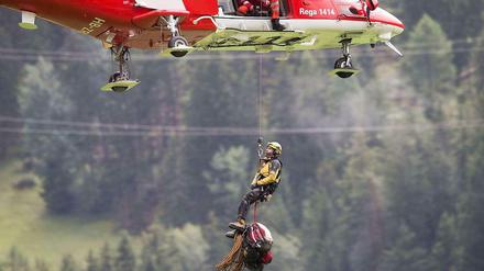 Von einer Hubschrauberbesatzung lässt sich ein Retter zu einem am Abgrund hängengebliebenen Waggon bei Tiefencastel abseilen.