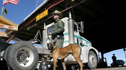 Ein US-Grenzbeamter sucht mit einem Drogenspürhund nach illegaler Fracht.