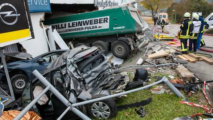 Mitarbeiter von Feuerwehr und Technischem Hilfswerk stehen am 13.10.2015 an einem Autohaus in Meiningen (Thüringen), nachdem ein LKW bei einem Unfall in das Autohaus gefahren war und dabei weitere Fahrzeuge beschädigt hatte.