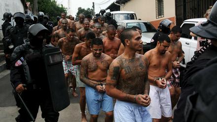 Mitglieder der Gang Mara Salvatrucha in El Salvador werden von Polizisten ins Gefängnis begleitet. 