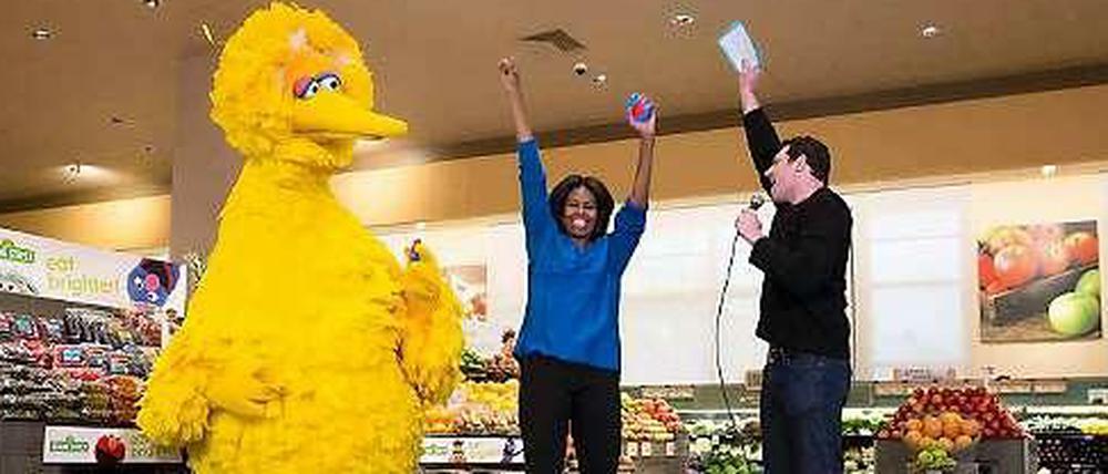 Michelle Obama (m) mit "Bibo", dem gelben Vogel aus der Kindersendung "Sesamstraße", und dem Moderator der US-Sendung "Funny or Die" im Supermarkt.