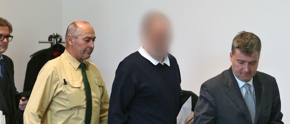 Ein wegen des Missbrauchs von rund 20 Jungen angeklagter Kinderarzt wird am 23.11.2015 im Strafjustizzentrum Augsburg (Bayern) zwischen seinen Anwälten Ralf Schönauer (r) und Moritz Bode (l) in einen Gerichtssaal geführt. Der Mann wurde am Donnerstag zu mehr als 13 Jahren Haft verurteilt. 