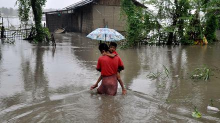 Ein Vater trägt im indischen Lakhimpur seinen durch ein überflutetes Gebiet. 