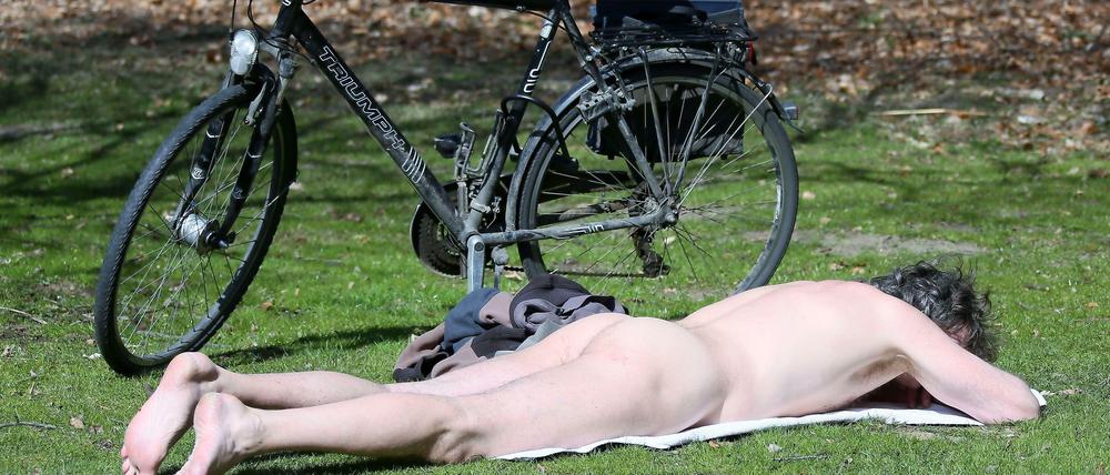 Nackter Mann mit Rad ruht sich in der Sonne aus.