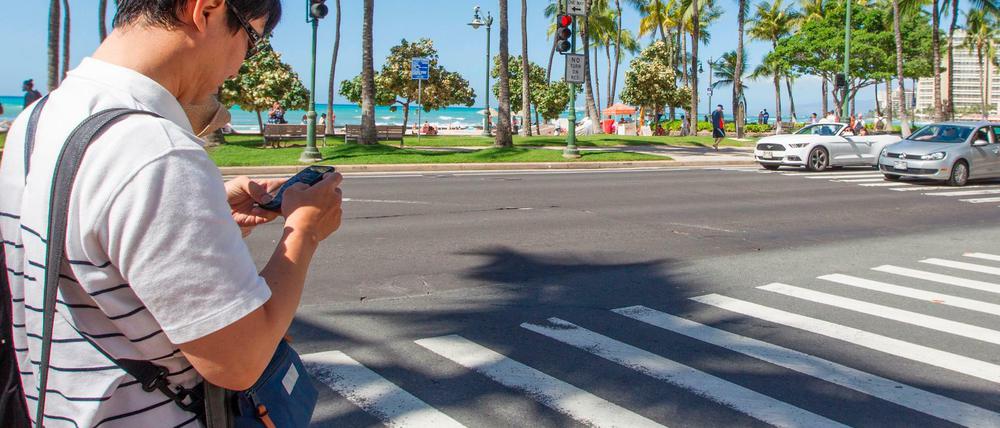 Das könnte teuer werden: Ein Fußgänger mit einem Mobiltelefon auf einem Zebrastreifen in Honolulu. 