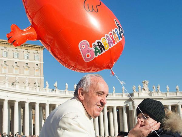 Sogar der Papst macht mit. Ein Kind hält eine aufblasbare Barbapapa-Figur in die Höhe und wird dabei vom Pontifex geherzt.