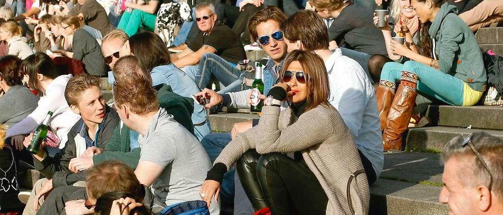 Temperaturrekord. Bei 23 Grad sitzen Menschen in Düsseldorf auf den Stufen und genießen die Sonne.