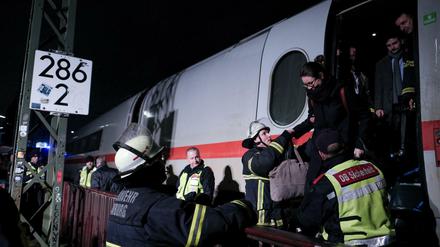 Feuerwehrleute und Mitarbeiter der DB-Sicherheit helfen in Hamburg Bahnreisenden aus einem ICE.