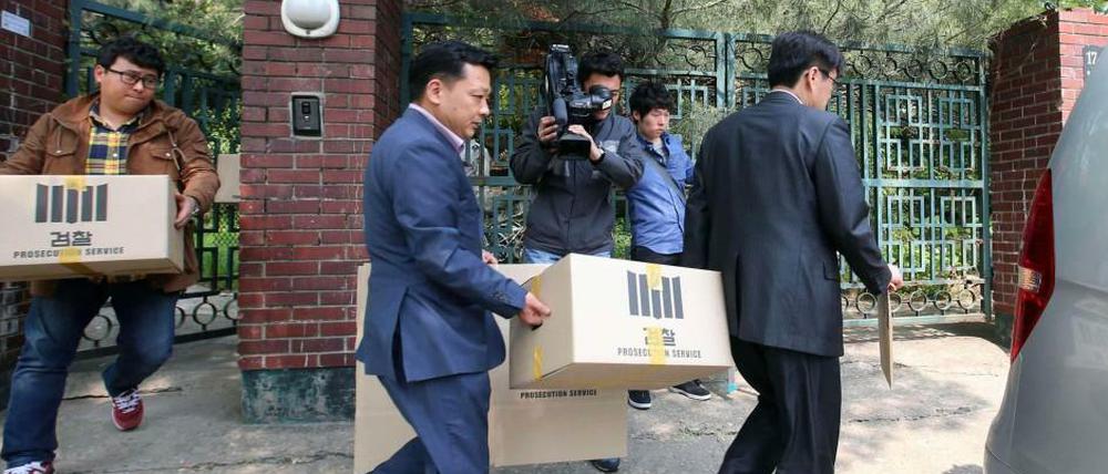 Ermittler tragen Kisten mit Akten aus einem Büro in Seoul.