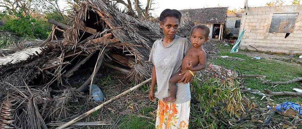 Mutter und Kind vor einer zerstörten Hütte auf Vanuatu. 