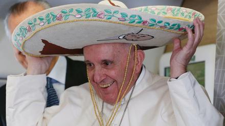 Papst Franziskus lacht und setzt sich auf dem Flug nach Havanna einen Sombrero auf. Den Mexikanern gefällt.