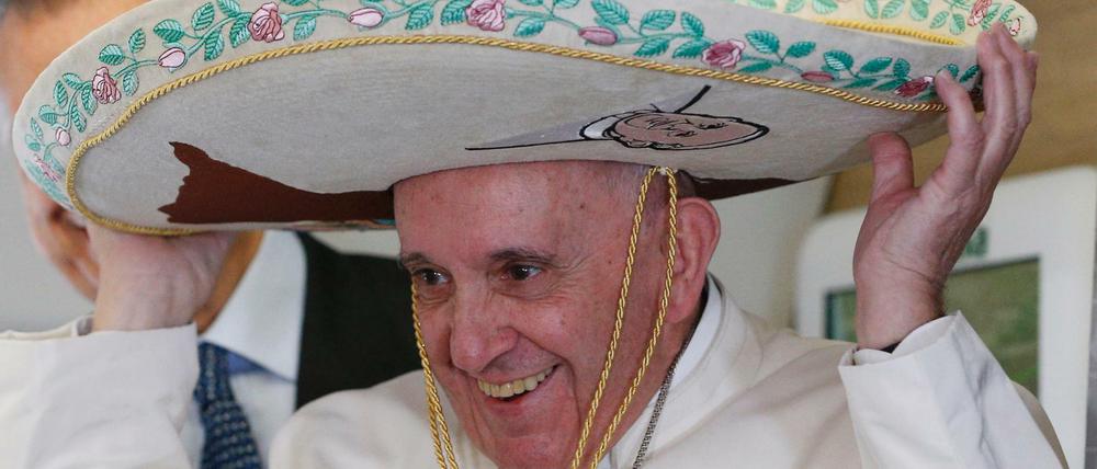 Papst Franziskus lacht und setzt sich auf dem Flug nach Havanna einen Sombrero auf. Den Mexikanern gefällt.