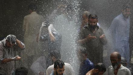Menschen in Karachi, Pakistan, kühlen sich mit Wasser ab, das aus einem Loch in einer Pipeline schießt. Bisher sind bei der Hitzewelle mehr als tausend Menschen ums Leben gekommen. 