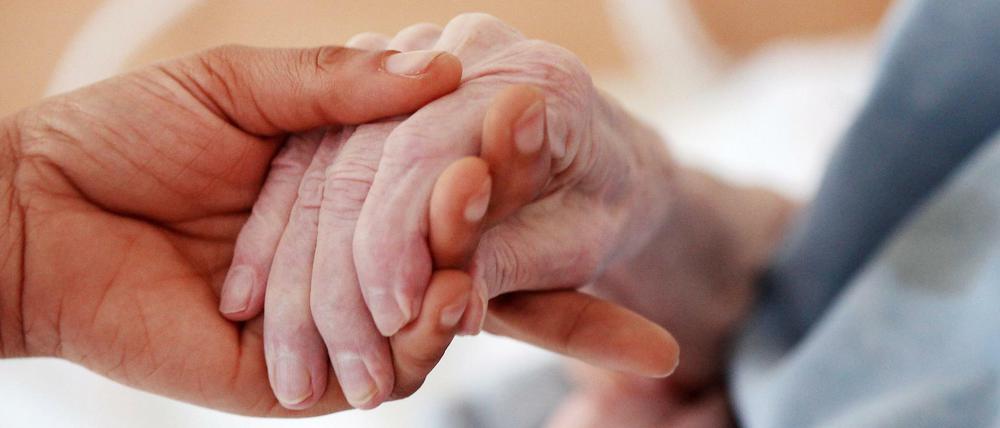 Eine Pflegerin hält einem Altenheim die Hand einer Bewohnerin. (Symbolbild)