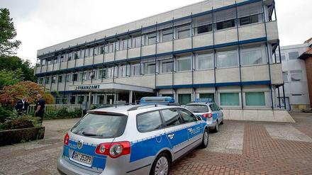 Polizeifahrzeuge stehen am 01.09.2014 in Rendsburg (Schleswig-Holstein) vor dem Finanzamt. Im Prozess nach den tödlichen Schüssen auf einen Abteilungsleiter des Rendsburger Finanzamtes wurde am Dienstag das Urteil gegen den 55-jährigen Täter gesprochen.