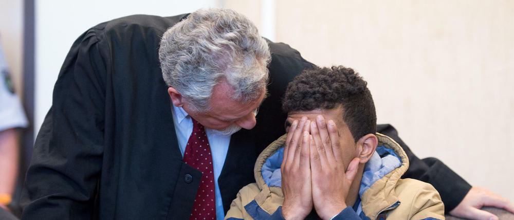 Der angeklagte Algerier sitzt am 06.05.2016 im Amtsgericht in Köln neben seinem Verteidiger Rüdiger Buhr auf der Anklagebank und hält sich die Hand vor das Gesicht. Der 23-Jährige muss sich wegen Raubes und versuchten Diebstahls verantworten. Sein Bruder ist wegen versuchter sexueller Nötigung angeklagt. 