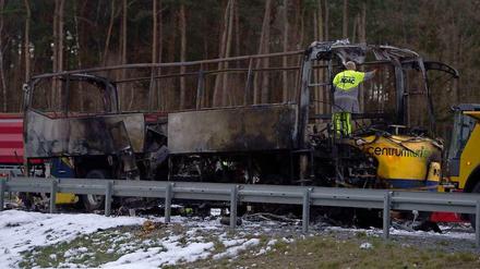 Ein Mitarbeiter des ADAC steht am Montag auf der Autobahn 13 nahe Ortrand (Brandenburg) in einem ausgebrannten dänischen Reisebus.