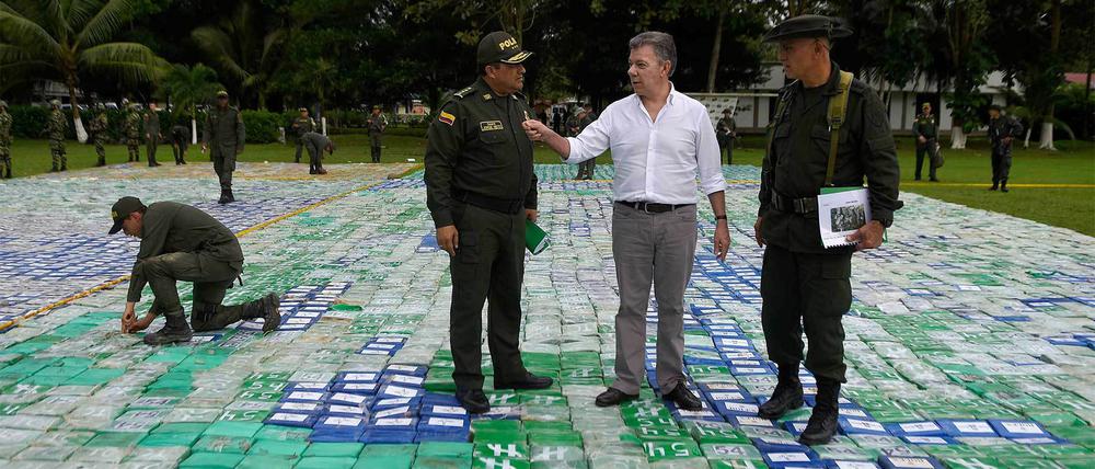 Der kolumbianische Präsident Juan Manuel Santos (M) und General Jorge Nieto (l) stehen auf einem großen Kokainfund. 