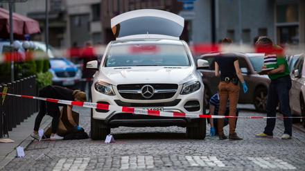 Mitarbeiter der Spurensicherung untersuchen den Tatort am weißen Mercedes-Geländewagen in Frankfurt am Main. 