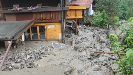 Von Schlamm und Gestein sind Häuser in Oberstdorf (Bayern) am Sonntag umgeben nachdem andauernder Regen eine Schlammlawine ausgelöst hatte. Ein bedrohtes Wohngebeit mit bis zu 500 Menschen wurde vorsorglich evakuiert.