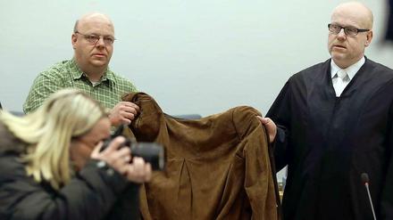 Eine 32 Jahre alte Frau wird am Dienstag in Siegen (Nordrhein-Westfalen) von ihrem Anwalt Daniel Nierenz (r) und einem Anwaltsgehilfen (hinten links) mit einer Jacke verdeckt. Die Frau muss sich vor dem Landgericht wegen des Todes ihrer beiden Kinder verantworten. 