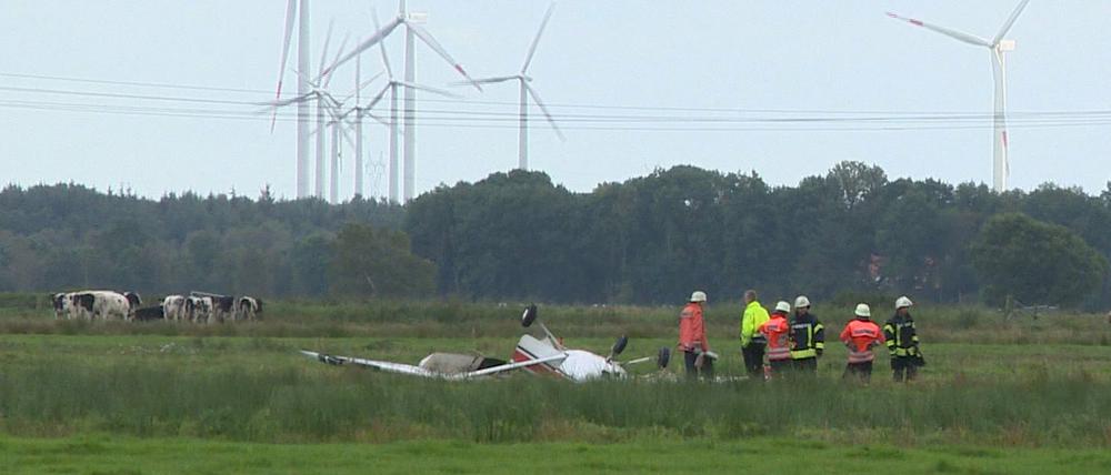 Feuerwehrleute neben einem abgestürzten Sportflugzeug auf eine Wiese nahe Sandstedt bei Cuxhaven (Niedersachsen). Drei Menschen kamen bei dem Unglück ums Leben. 