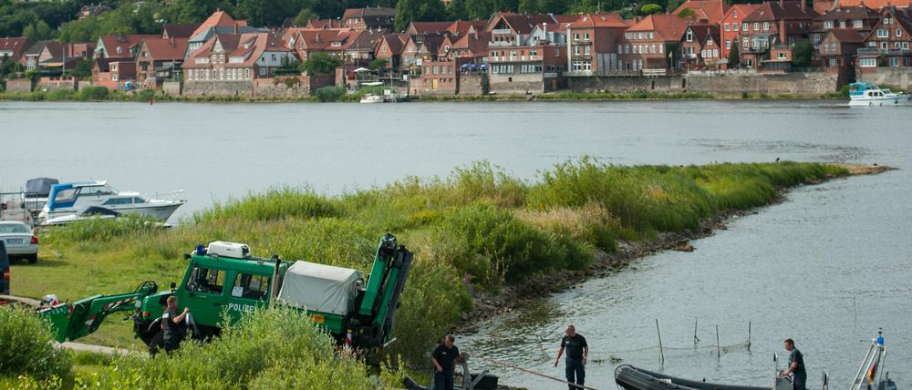 Ein Einsatzfahrzeug die Polizei zieht am 01.08.2015 bei Hohnstorf/Elbe (Niedersachsen) am Elbufer ein Polizeiboot aus dem Wasser. Nach dem Fund der Leiche des Familienvaters sucht die Polizei weiter nach der ebenfalls vermissten Mutter und Tochter.
