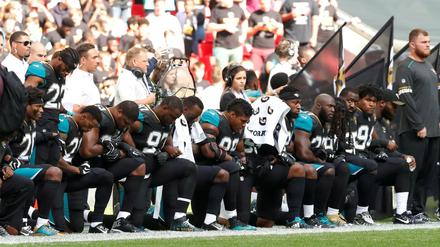 Protest am Spielfeldrand. Die Footballer des NFL-Teams Jacksonville Jaguars knien gemeinsam während der Nationalhymne nieder.