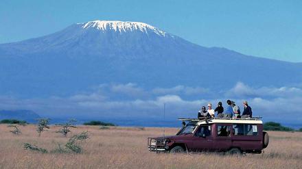 Touristen durchqueren in einem Jeep den Amboseli Nationalpark am Fuße des Kilimandscharo in Tansania.