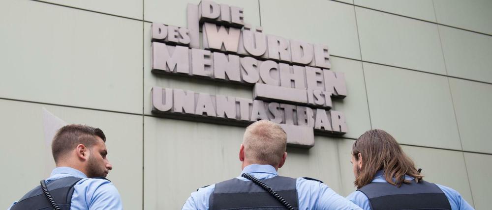 Drei Polizisten bewachen am 15.09.2014 das Oberlandesgericht in Frankfurt am Main (Hessen), wo der Prozess gegen ein mutmaßliches Mitglied der Terrormiliz Islamischer Staat (IS) stattfindet.