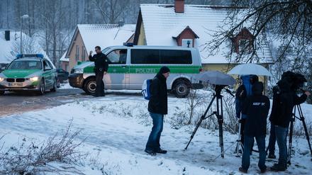 Medienvertreter stehen vor zwei Polizeifahrzeugen am 04.01.2015 in Oberaurach (Bayern) in der Nähe des Ortes, an dem in der Silvesternacht ein 11-jähriges Mädchen durch einen Kopfschuss getötet worden war. 