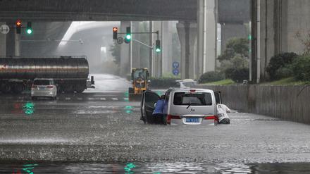 Menschen schieben nach starken Regenfällen in Zhengzhou in der zentralen chinesischen Provinz Henan einen Lieferwagen durch Hochwasser. 
